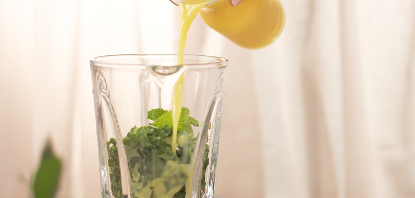 pouring florida orange juice into a blender with kale